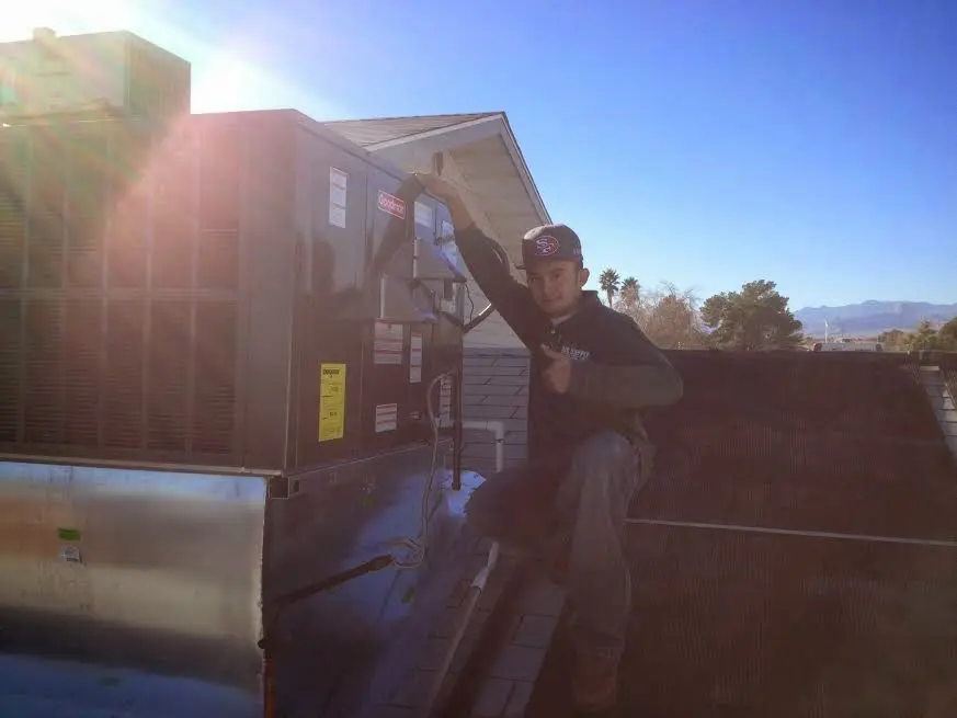 HVAC technician performing Heat Pump Repair on a rooftop unit in Ward